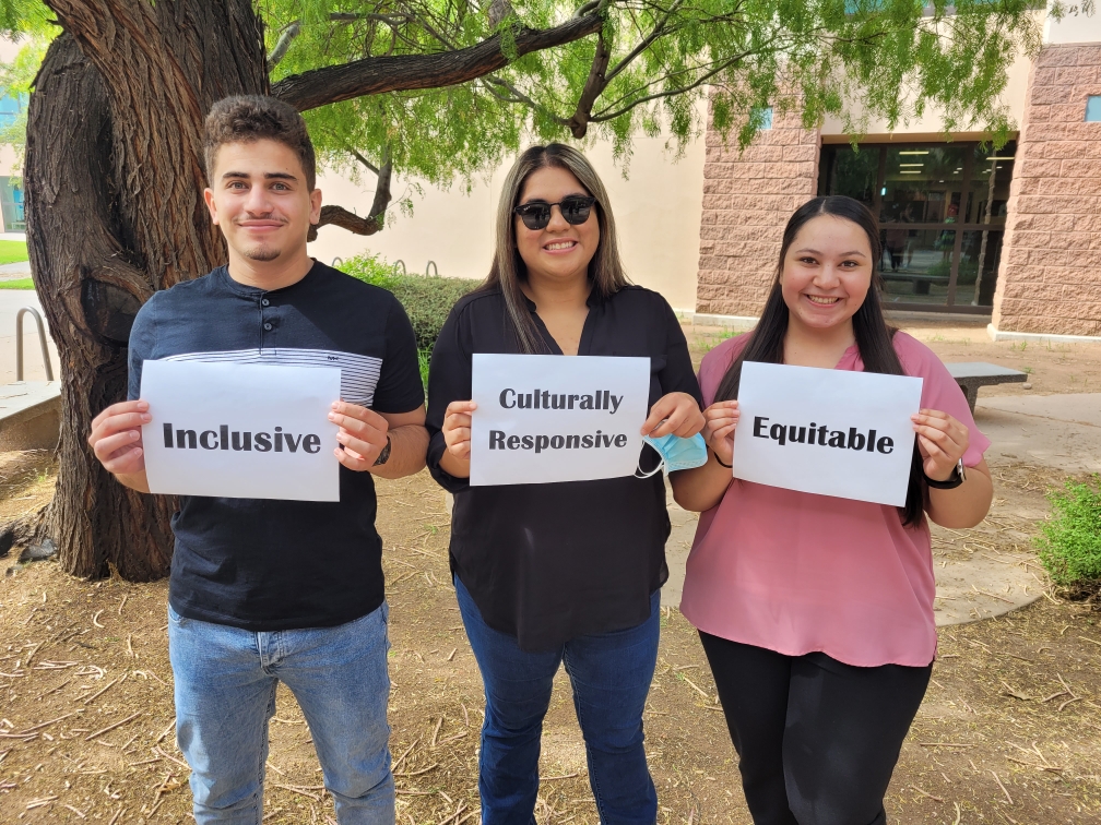 Three DACC students holding up signs that say Inclusive, Culturally Responsive, and Equitable